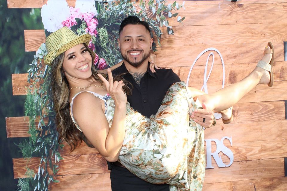 A couple posing in front of a floral backdrop